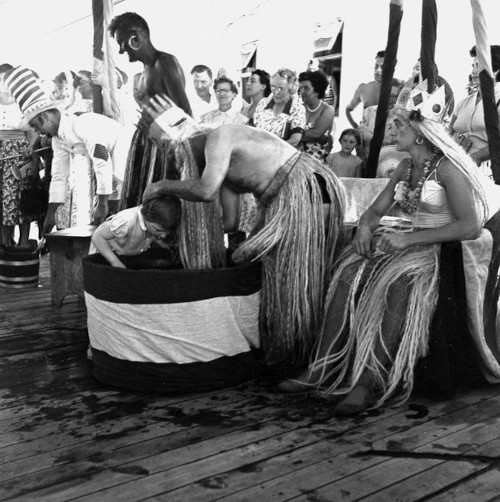 Small child about to get her head dipped in water as part of a 'crossing the equator' King Neptune ceremony onboard the Union-Castle cruise ship.